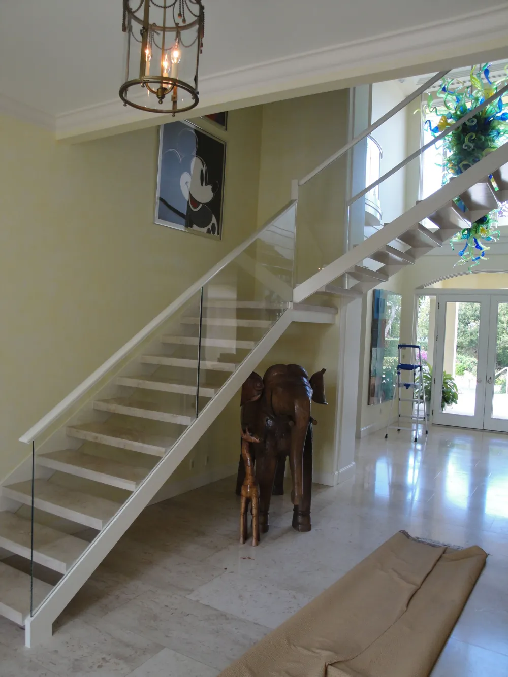 White floating stair with glass balustrade and blue-green glass chandelier